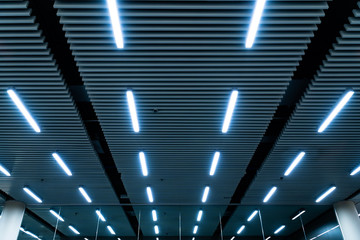 Leading lines and low light view. Fluorescent lamps open in row on the ceiling beautiful and modern inside the building.