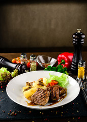 Poster - White plate of pork medallions with mushroom sauce on weathered wooden table.