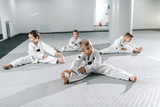 Small group of Caucasian sporty children stretching and warming up before their taekwondo training.
