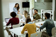 © BGStock72 - Smiling young woman standing near whiteboard and shaking hand to her female colleague