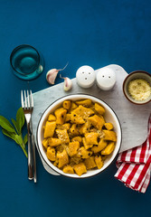 Wall Mural - Italian gnocchi from pumpkin with parmesan cheese in a plate on a blue background. traditional dishes