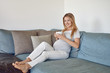 © Lars Zahner - Schwangere junge Frau sitzt mit Tee auf der Couch