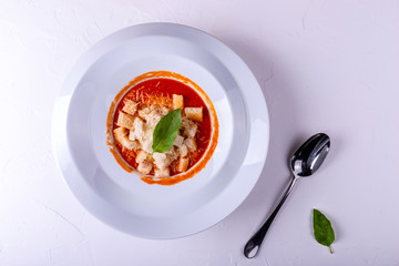 Wall Mural - Tomato cream soup with crackers in a white plate on a white background.