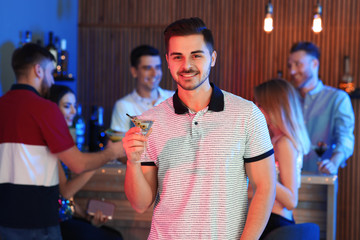 Wall Mural - Young man with glass of martini cocktail at party