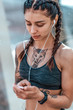 © byswat - Woman athlete in tattoos, summer in city, resting after workout fitness. Sportswear top. Headphones smartphone. Online application social networks. Listening to music. Communication on the Internet.