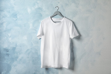 Hanger with white t-shirt on color background. Mockup for design