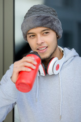 Wall Mural - Smiling young latin man drinking water portrait format winter sports training fitness