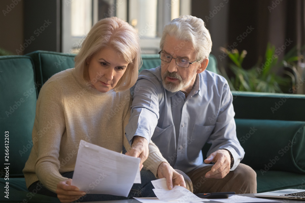 Serious grey haired mature couple calculating bills, checking finances together - obrazy, fototapety, plakaty 