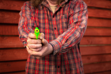 A man in a plaid shirt holding a toy gun. the man pointed the gun at the viewer