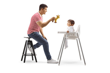 Canvas Print - Father holding a toy and animating a baby in a chair