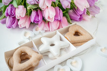 Biscuit Gingerbread Cookies In The Shape Of A Star And Heart Against The Backdrop Of A Beautiful Festive Bouquet Of Tulips