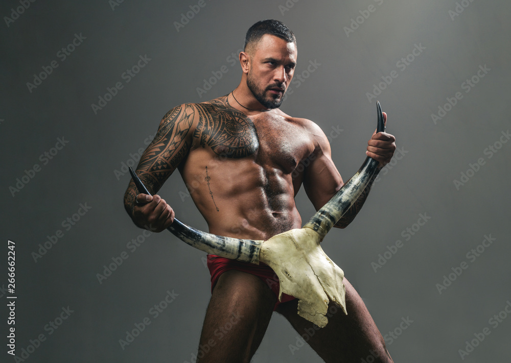 Desire is the energy force. Sexy latino man showing his sexual desire and attraction. Muscular hispanic man with fit body holding skull and horns. Attractive power and desire force. Desire concept - obrazy, fototapety, plakaty 