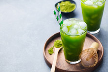 Matcha Ice Tea In Tall Glass On Wooden Plate. Grey Stone Background. Copy Space.