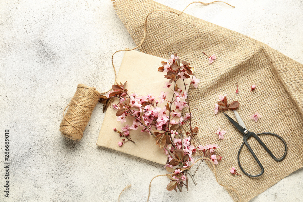 Notebook, thread, scissors and beautiful blossoming branches on light background