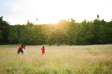 father takes a photo of his daughter in the garden,field, evening, sunset, family time, warm feeling