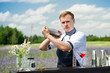 © smspsy - catering bar service, barman show. Handsome bartender preparing cocktails near the bar counter, outdoors