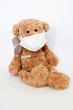 brown soft toy bear sick with a bandage on his nose and a medical thermometer