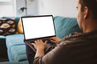 © guteksk7 - Man using laptop blank screen while sitting on sofa