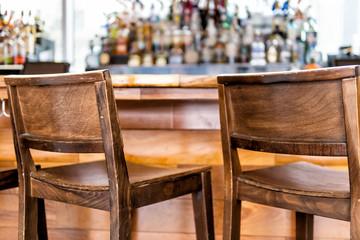 Empty wooden vintage bar stools counter row in drink establishment pub during day closeup of retro wood and nobody