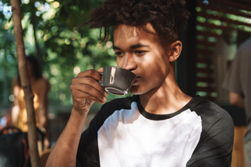 Sticker - Smiling african young man drinking coffee at the cafe