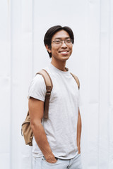 Poster - Smiling young asian man student carrying backpack