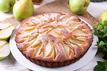 Homemade pear pie on a white table with pears