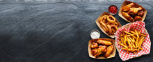 Pub Appetizers Such As Chicken Wings, Onion Rings And French Fries In Panoramic Composition