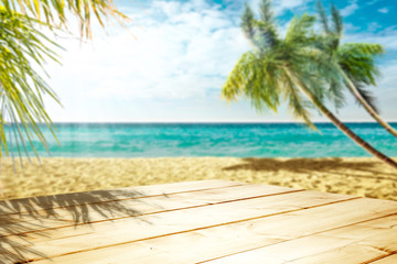 Wall Mural - Wooden table background of free space and summer beach with palms. 