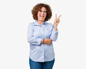 Beautiful middle ager senior businees woman wearing glasses over isolated background smiling with happy face winking at the camera doing victory sign. Number two.