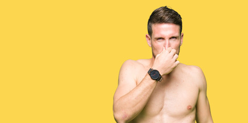 Poster - Handsome shirtless man showing nude chest smelling something stinky and disgusting, intolerable smell, holding breath with fingers on nose. Bad smells concept.