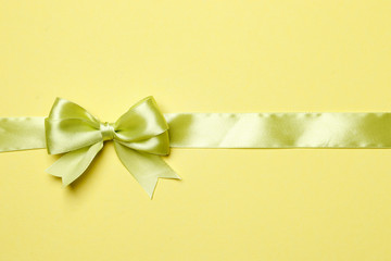 Light green ribbon and bow on a green background. The concept of gifts.