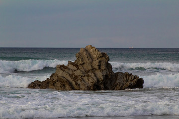 Large rock half submerged in the sea water. On the beach of Atxabiribil, in Sopelana, vizcaya