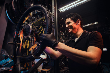 Wall Mural - Diligent attractive mechanic is fixing bicycle at his own workshop.