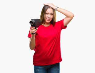 Sticker - Young beautiful caucasian woman filming using vintage video camera over isolated background stressed with hand on head, shocked with shame and surprise face, angry and frustrated. Fear and upset