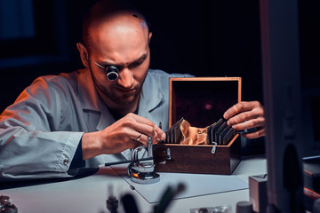 Wall Mural - Focused man is working at his workshop with monocle and other tools repairing old watches.