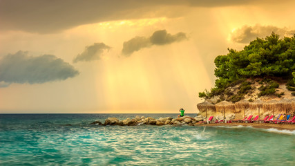 Scenic, famous Kalogria beach sun rays in Greece and man taking a photo with his smartphone