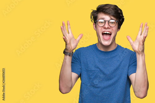 Fotografía Young handsome man wearing glasses over isolated background celebrating crazy and amazed for success with arms raised and open eyes screaming excited
