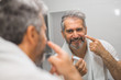 middle aged man using skin cream in bathroom