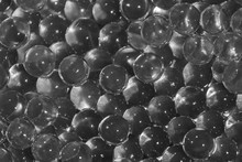 Water Black Gel Balls With Bokeh. Polymer Gel. Silica Gel. Balls Of Black Hydro-gel. Crystal Liquid Ball With Reflection. Black Balls Texture Background