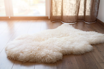 Sheep skin on the laminate floor in the room. Cozy place near the window. Sunny day