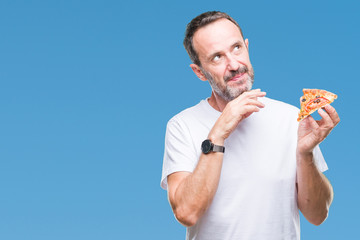 Middle age hoary senior man eating pizza slice over isolated background serious face thinking about question, very confused idea