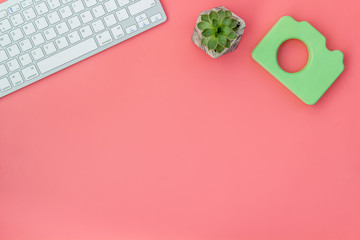 Blogger table design with photo camera, keyboard and plant on red background top view mockup