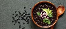 Thick Black Bean Soup Or Stew. Latin American Or Mexican Cuisine. Stewed Black Beans Served With Avocado And Red Onion And Cilantro. Place For Text. Top View.