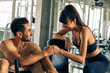 Two young and healthy happy smiling Caucasian workout buddies doing fist bump in sportswear inside gym - fitness training support achievement concept