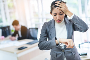 Young attractive Asian business woman looking at the watch time worried and afraid of getting late to meeting with boss or customer.