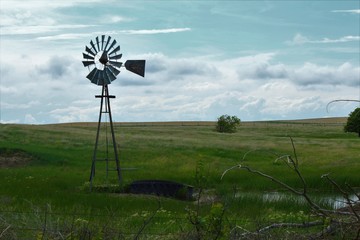 Kansas Country Windmill in a pasture with grass and a blue sky with clouds