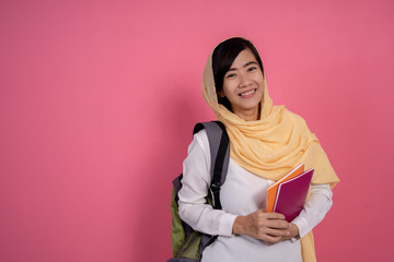 Wall Mural - portrait of happy young muslim student smiling over pink background