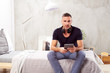 © chika_milan - Caucasian man in forties sitting on bed in bedroom and using tablet.