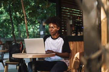 Canvas Print - Young african man using laptop computer at the cafe