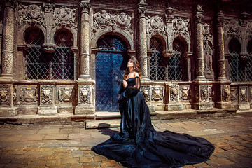 Wall Mural - Beautiful princess in lush black dress on background of Gothic cathedral. Lviv, Ukraine